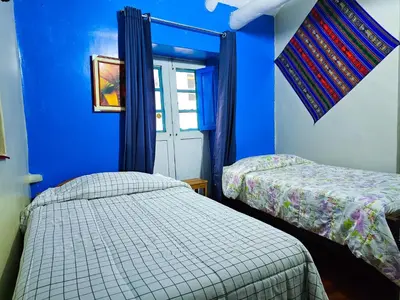 two beds in a room with blue walls at Hospedaje Euro's De San Blas in Cusco