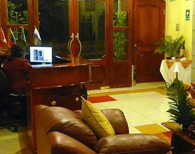 a living room with a leather couch and a desk at Hotel Inkayra in Cusco