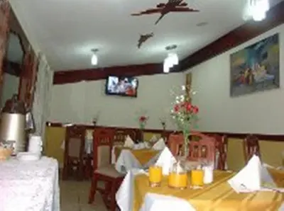 a dining room with two tables and a tv on the wall at Hotel Inkayra in Cusco
