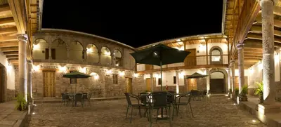 a patio with chairs and tables with umbrellas at night at Tierra Viva Cusco Centro in Cusco