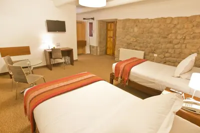 a hotel room with two beds and a stone wall at Tierra Viva Cusco Centro in Cusco