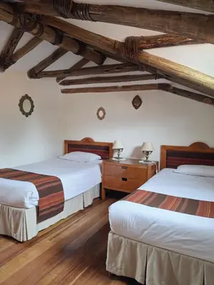 two beds in a room with wooden ceilings at Casona La Recoleta in Cusco