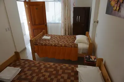a small room with two beds and a window at Hostal Camiluz in Nazca