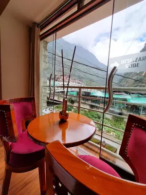 a table and chairs in a room with a large window at Hs Tierra In in Machu Picchu