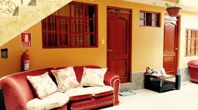 a living room with a red couch and a staircase at Kuska Hostal in Cusco