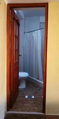 a bathroom with a white toilet and a shower at Kuska Hostal in Cusco