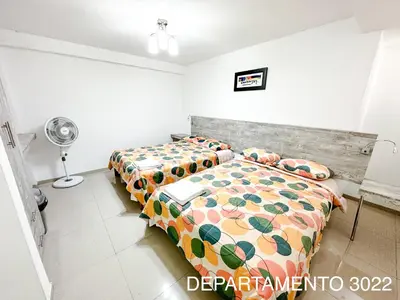 a bedroom with two beds and a table and a fan at Departamento Miraflores in Lima