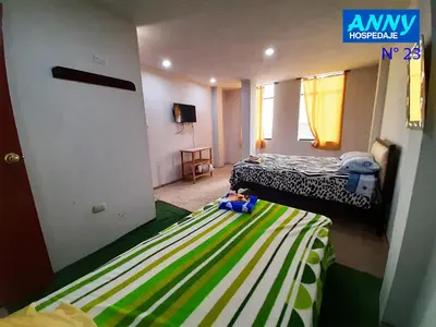 a small room with two beds and a door to a bedroom at Hospedaje Anny in Larán