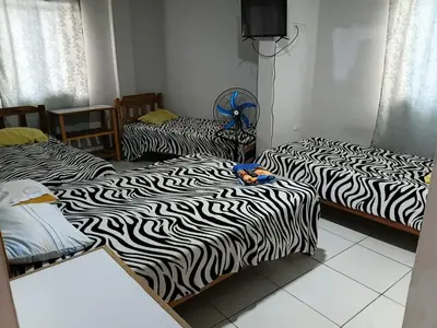 two beds with black and white sheets in a room at Hospedaje Anny in Larán
