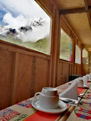 a table with a coffee cup on a table with a window at Soraypampa Hostel - Private Cabins & Dorms for Self-Guided Humantay & Salkantay Trek -Comidas-hot shower-wifi-Pack horses in Salcantay