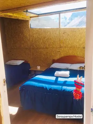 a bedroom with a blue bed and a window at Soraypampa Hostel - Private Cabins & Dorms for Self-Guided Humantay & Salkantay Trek -Comidas-hot shower-wifi-Pack horses in Salcantay