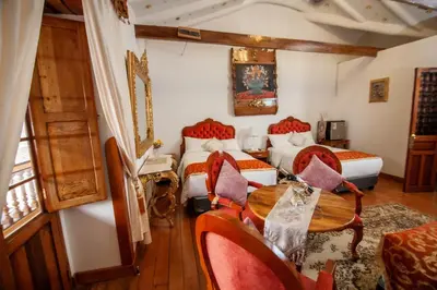 a bedroom with two beds and a table and chairs at Casona Corrales Hotel Boutique in Cusco
