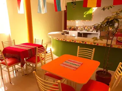 a restaurant with an orange table and chairs and a counter at Marlon's House Nasca in Nazca