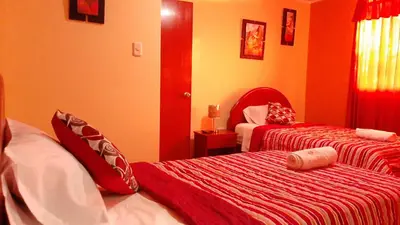 a bedroom with two beds with red and white sheets at Marlon's House Nasca in Nazca