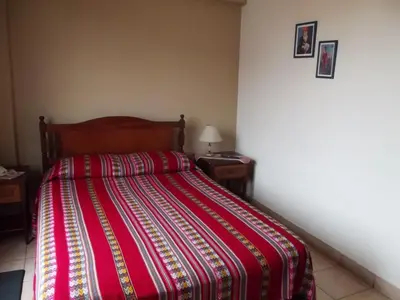 a bedroom with a bed with a red and orange striped blanket at Hostal Gemina in Lima