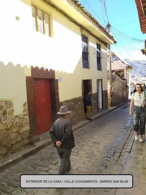 a man in a hat walking down a street at Munay San Blas Wasi in Cusco
