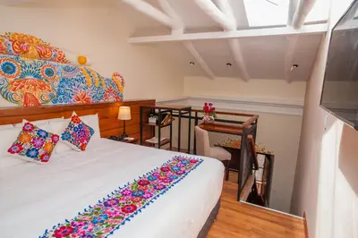 a bedroom with a white bed with a colorful blanket at Casa Biru Hotel Boutique in Cusco