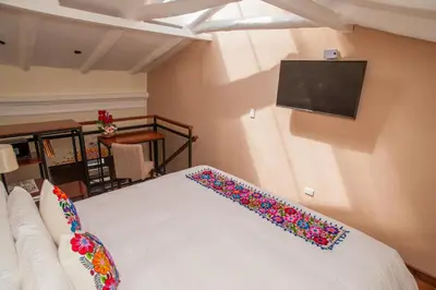 a bedroom with a bed and a tv on the wall at Casa Biru Hotel Boutique in Cusco