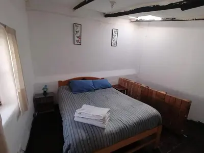 a small bedroom with a bed with blue pillows at Asiriq Wasi Casita de huéspedes in Cusco