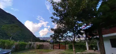 a view of a house with a fence and mountains at Casa Hospedaje el Prado Eco turismo in Oxapampa