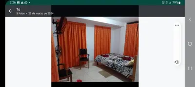 a bedroom with orange curtains and a bed in a room at Hotel Quilla Wasi in Lunahuaná