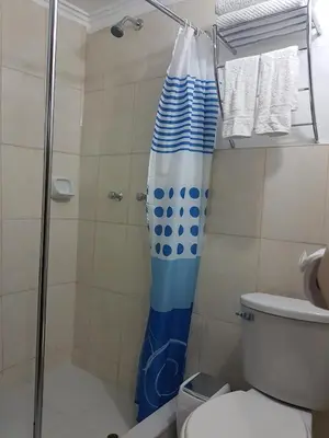 a shower with a blue and white shower curtain in a bathroom at Kurumi Hostel in Cusco