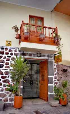 a building with a balcony and a door with potted plants at Conquista Cusco in Cusco