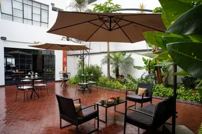 a patio with chairs and tables and an umbrella at Lima 18 Boutique in Lima