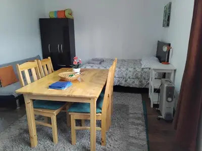 a wooden table and chairs in a room with a bed at Nice studio in historic center with private bathroom and kitchen! in Cusco