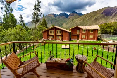 a deck with two chairs and a house with mountains at NUNA by DCO in Urubamba
