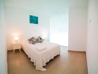a white bedroom with a bed with pillows on it at Departamento de playa - Condominio OCEAN REEF - SAN BARTOLO in San Bartolo
