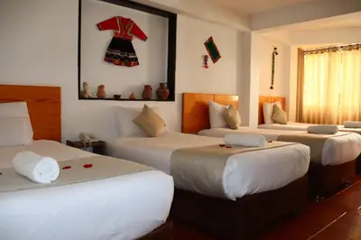 a bedroom with three beds and a dress on the wall at Fenix Hotel Machupicchu in Machu Picchu