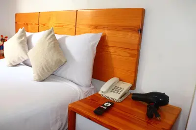 a bed with a phone on a table next to a bed at Fenix Hotel Machupicchu in Machu Picchu