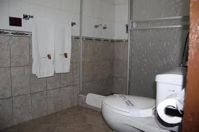 a bathroom with a toilet and a shower with towels at Hotel Marqueses in Cusco