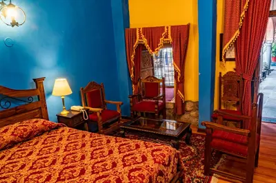 a bedroom with a bed and two chairs and a table at Hotel Marqueses in Cusco
