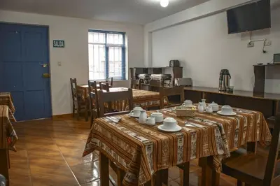 a dining room with two tables and a kitchen at Hotel Del Prado Hometown in Cusco