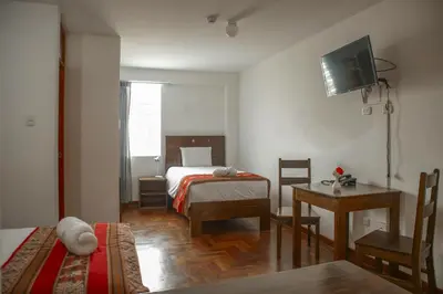 a bedroom with a bed and a table and a television at Hotel Del Prado Hometown in Cusco