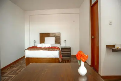 a hotel room with a bed and a vase of flowers on a table at Hotel Del Prado Hometown in Cusco
