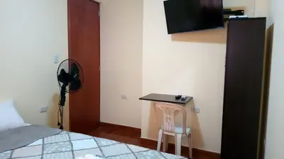 a bedroom with a bed and a desk with a television at Peruvian Wasi - Bed & Breakfast in Lima