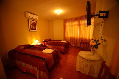 a hotel room with two beds and a table at Hotel Alegria Nasca in Nazca