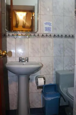 a bathroom with a sink and a toilet and a mirror at Wayras Hostal in Ollantaytambo