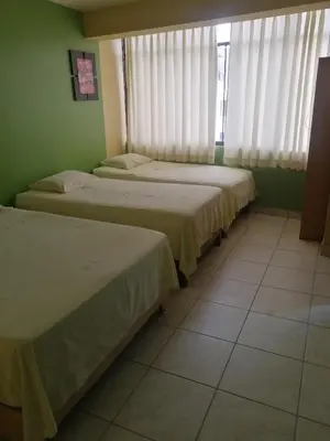 three beds sitting in a room with a window at Hostal Boulevard in Nazca