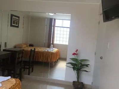 a bedroom with a bed and a table and a mirror at Hostal Sueños Breña in Lima