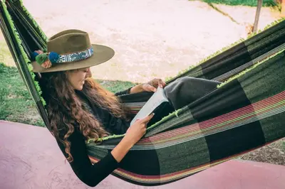 a woman sitting in a hammock reading a book at Valle verde, Hostel & camping in Urubamba