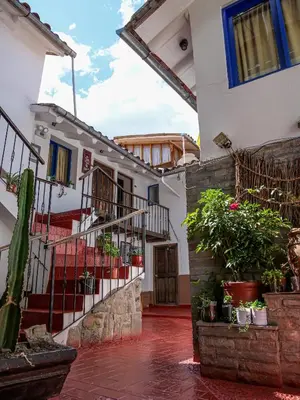 a building with stairs and potted plants in a courtyard at LO NUESTRO House in Cusco