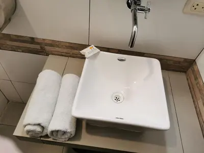 a white sink in a bathroom with towels on a shelf at Hotel Dia y Noche in Lima