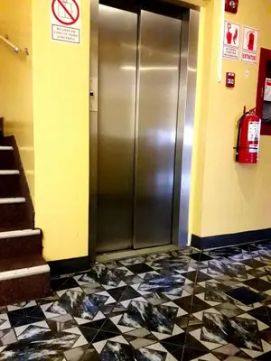 a metal elevator in a building with a tiled floor at Hotel Dia y Noche in Lima