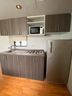 a kitchen with a stainless steel refrigerator and a microwave at Casa Caravanas in Paracas
