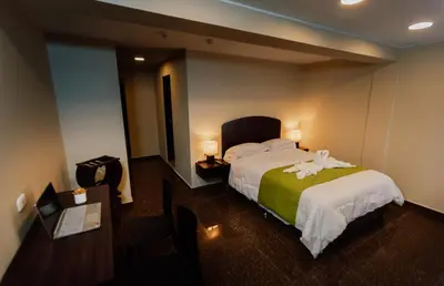 a hotel room with a bed with a green blanket at Real Hotel in Huánuco