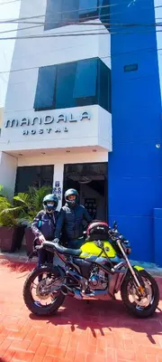 two people sitting on a motorcycle in front of a building at Mandala in Pisco